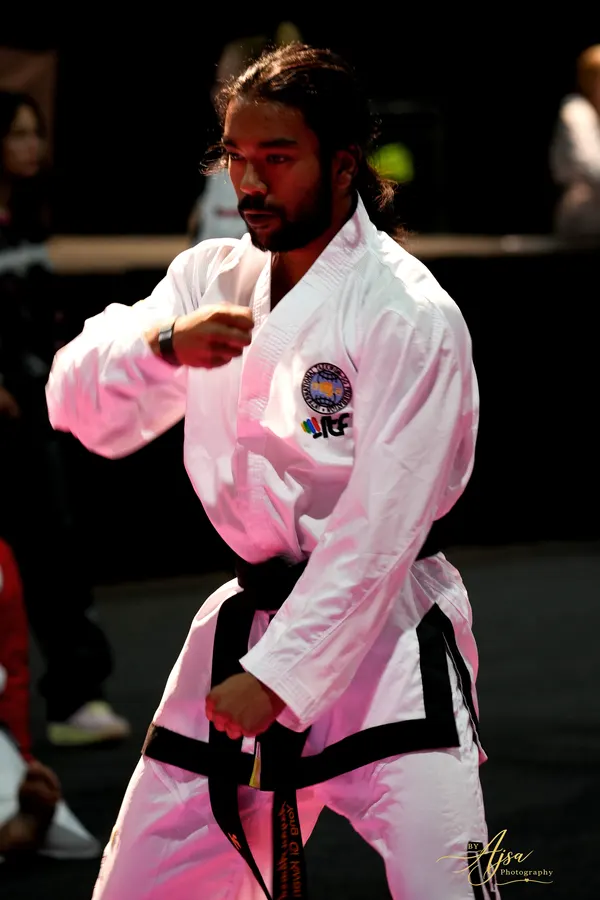 Black belt in a pattern movement under the lights