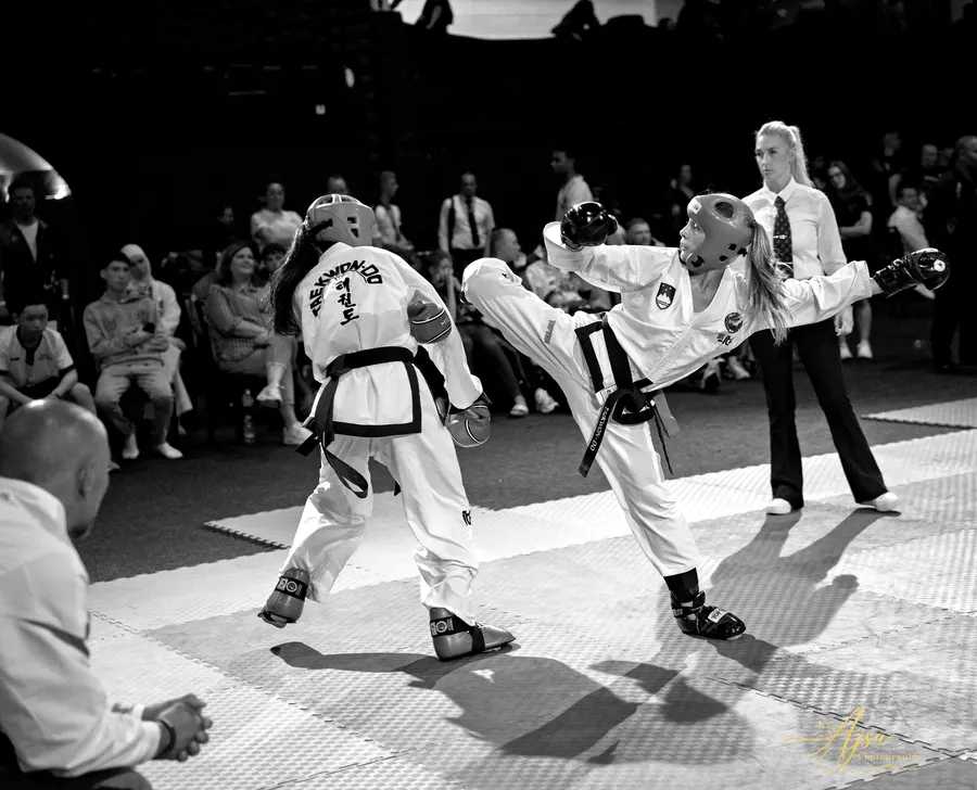 Black and white photo of a sparring exchange with a referee
